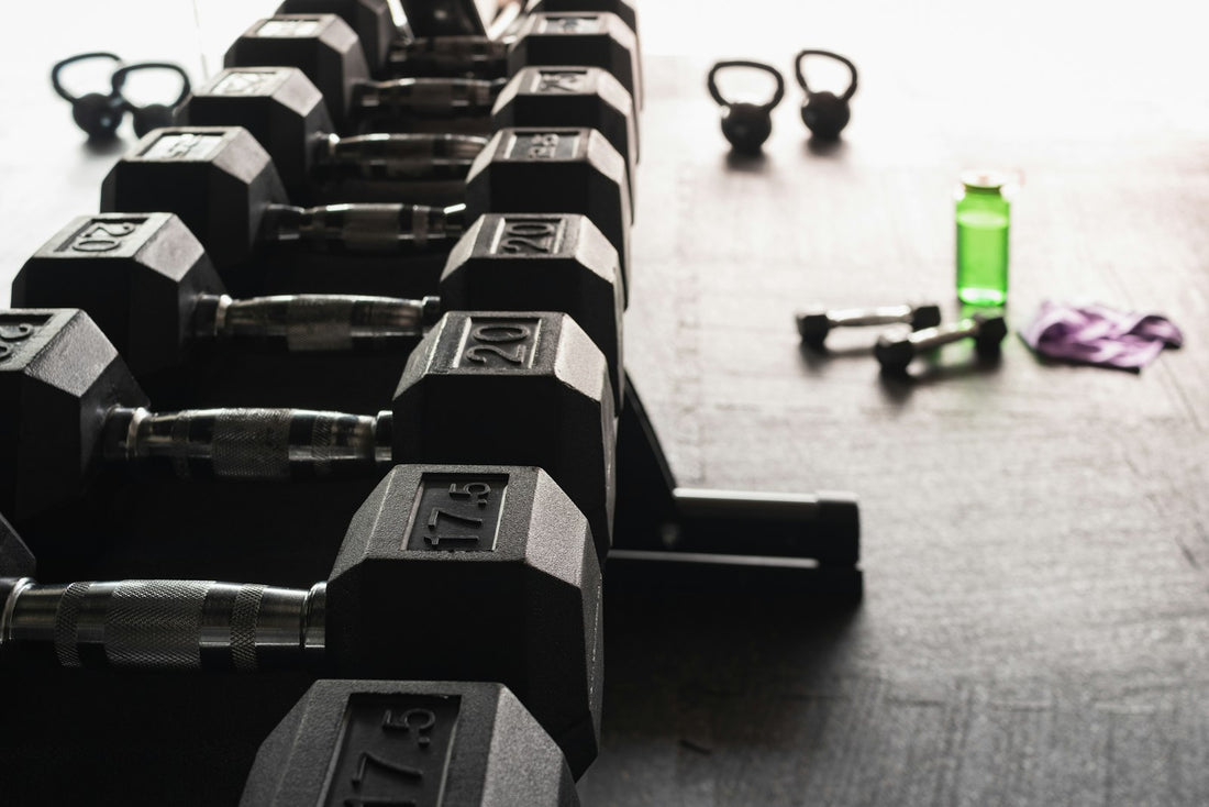 A row of black hex dumbbells on a rack in a bright gym